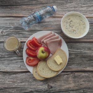 Zdjęcie przedstawia Dietę łatwostrawną (modyfikacja): Owsianka budyniowa z bananem i jabłkiem z posypką chia Bułka pszenna długa krojona Masło extra 82% Szynka Piastowska Sałata zielona ---> zamiana na pomidor Woda mineralna Jabłko pieczone ---> zamiana na jabłko